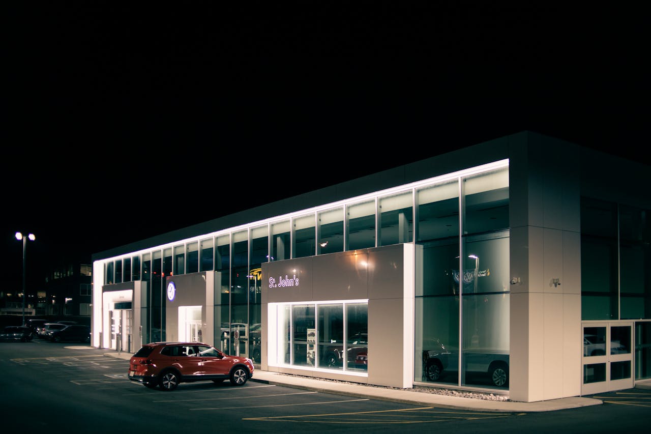 Off road car parked near entrance of shop with luminous lights at dark night